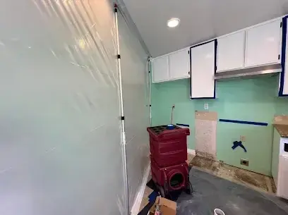 Containment plastic and a dehumidifier in a kitchen with the cabinets opened
